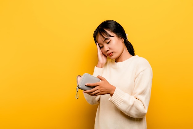 Lack of money financial problems Poor and poor Asian woman carrying empty bag trouble with no money in debt expenses isolated on yellow background