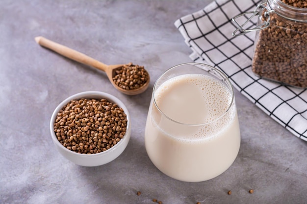 Lactose free dietary buckwheat milk in a glass and seeds in a bowl on the table