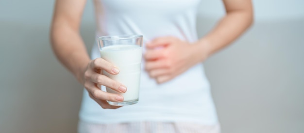 Photo lactose intolerance and milk allergy concept woman hold milk glass and having abdominal cramps and p