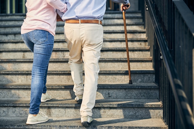 Lady assisting the man going up the stairs