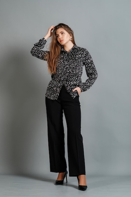 Lady in a blouse and trousers at grey background