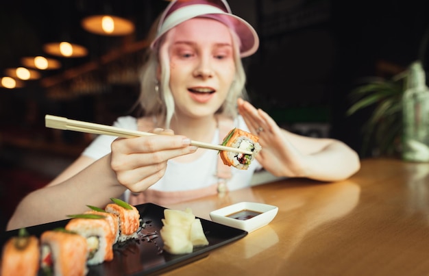 Photo lady eating sushi in an asian restaurant closeup photo of sushi in chopsticks