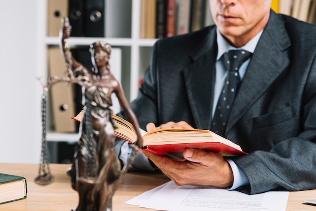 Photo lady of justice in front of lawyer reading law book in the courtroom