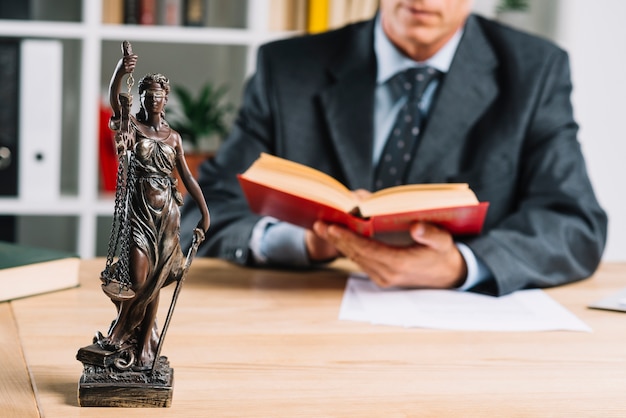 Lady of justice in front of male justice reading law book