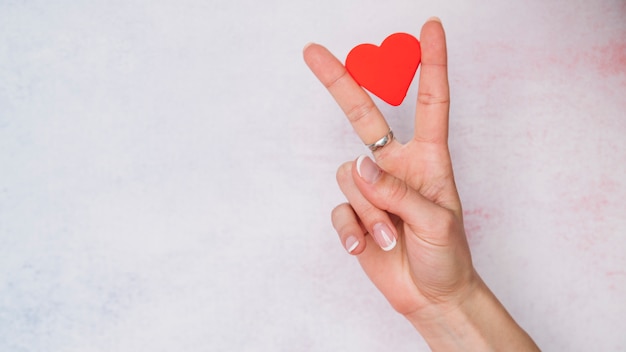 Photo lady's hand with paper heart between fingers