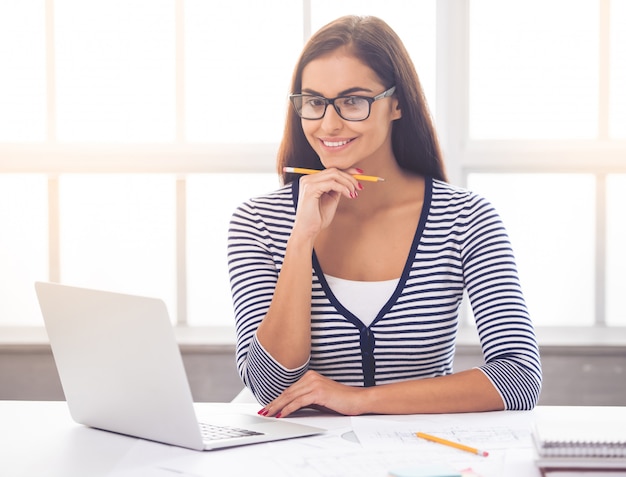 Lady in smart casual wear and eyeglasses is holding a pencil