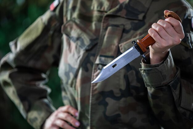 Photo a lady soldier holds a bayonet firmly in her hand and is ready to use it the army for special tasks