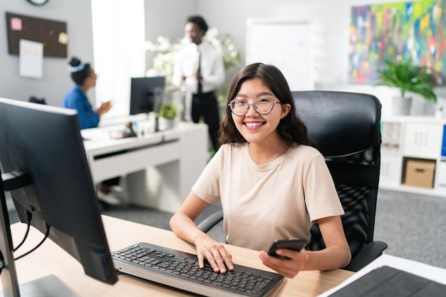 Lady with distinctive asian beauty works in an office at computer workstation looking for customer