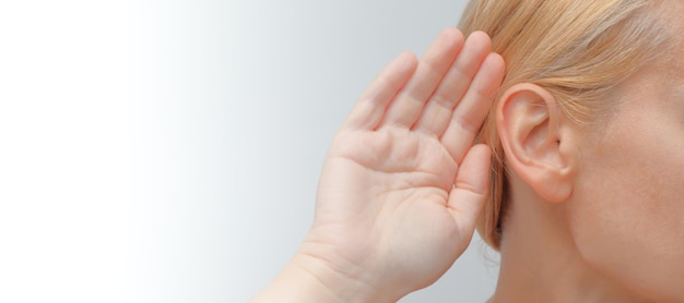 Photo lady with hearing aid put her hand to her ear young woman with hearing aid on light background