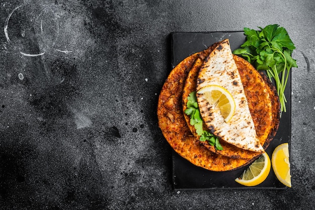 Lahmacun traditional Turkish pizza and wraps with salad on marble board with spices Black background Top view Copy space