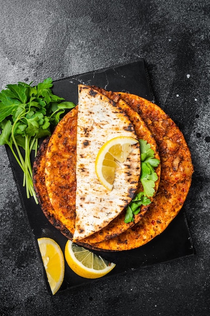 Lahmacun traditional Turkish pizza and wraps with salad on marble board with spices Black background Top view