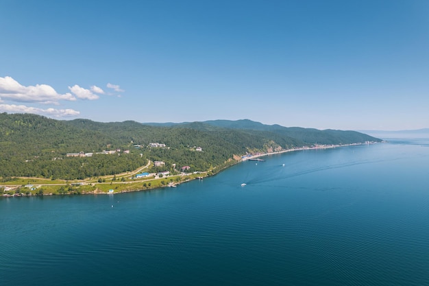 Lake Baikal is a marvelous blue jewel framed by scenic mountains and forests. Epic cinematic aerial view Lake Baikal. Aerial view of blue lake and green forests.