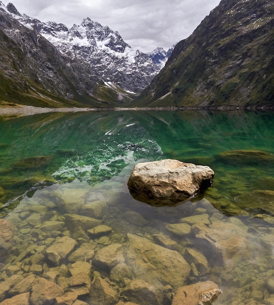 Lake Marian in the Darran Mountain Range under a cloudy sky in New Zealand