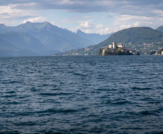 A lake Orta with a castle on St Julius Island and mountains in the background