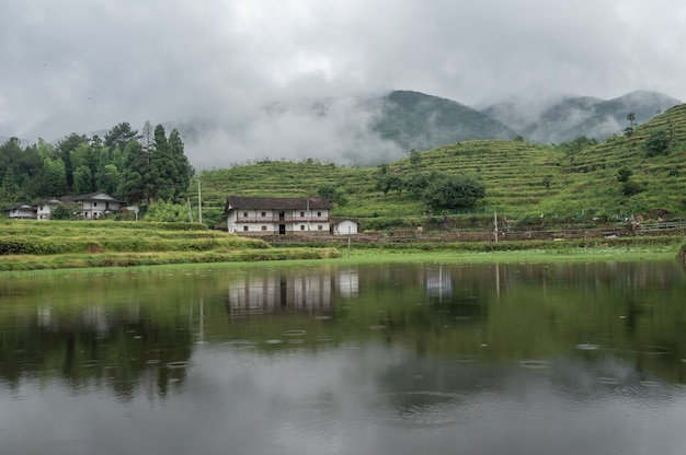 The lake reflected the mountain with houses and fog on the mountain