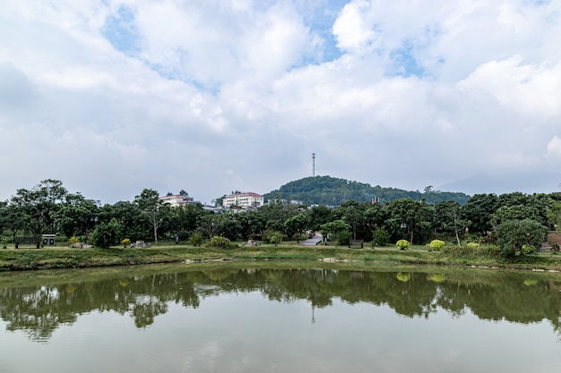 The lake reflects the countryside, white clouds and green trees