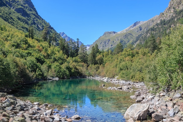 Lake scenes in mountains, national park Dombai, Caucasus, Russia, Europe. Sunshine weather, blue color sky, far away green trees. Colorful summer day, time