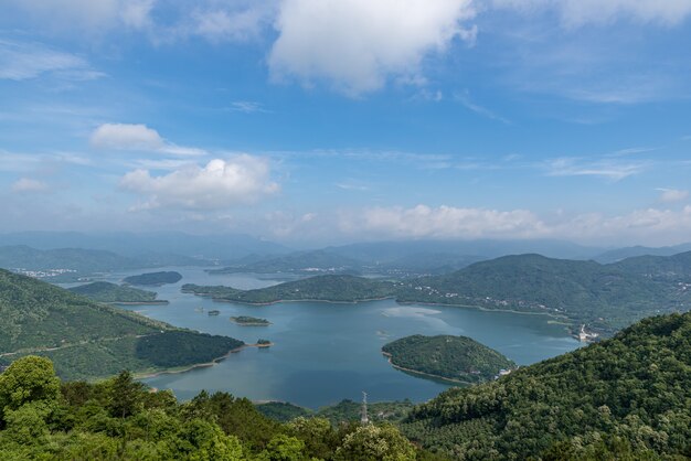 A lake surrounded by forests under blue sky and white clouds