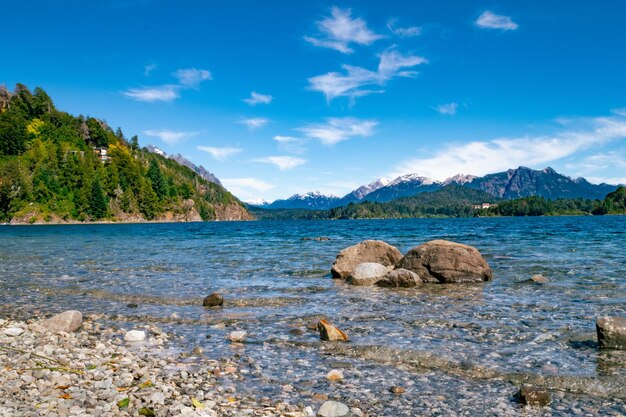 A lake with rocks and trees in the background and a mountain in the background