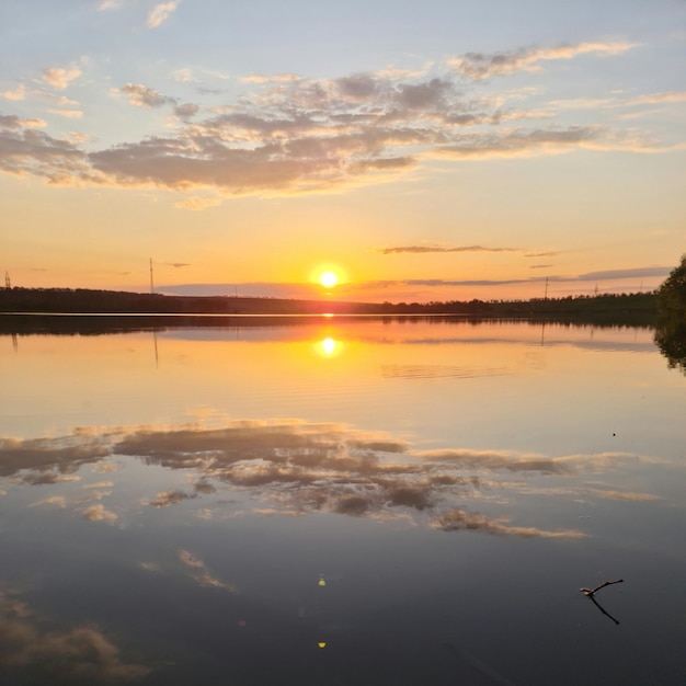 A lake with a sunset and a reflection of the sky and clouds.