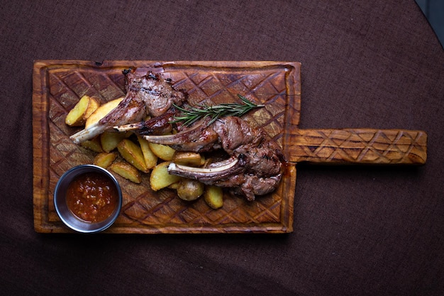 Lamb Chops and Potatoes on a Wooden Board with Dipping Sauce