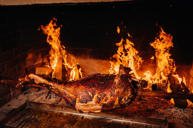 The lamb is cooked entirely on a spit on the fire Cooking