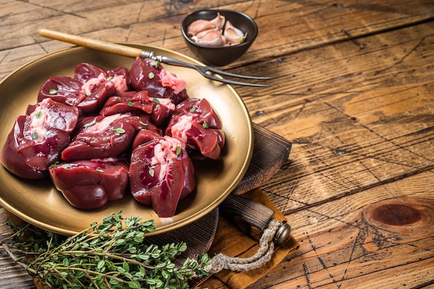 Lamb kidney raw sliced offal on plate with thyme Wooden background Top view Copy space