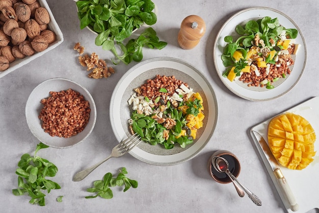 Lamb's lettuce salad with mango lentils and walnuts Top view at the kitchen table with cutlery dressing bowl and other ingredients