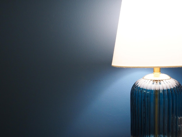 Lamp with white lighting in dark room with blue wall with copy space for text