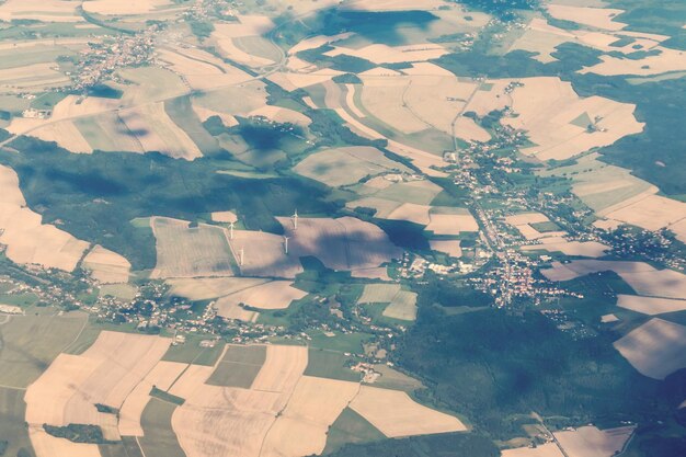 The land with meadows forests settlement and turbines view from above