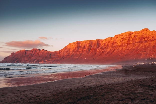 Landscape of beach and red mountains inbackground Seascape with peaceful feeling and moment Scenic place with ocean and sand Concept of summer travel holiday vacation beautiful outdoors