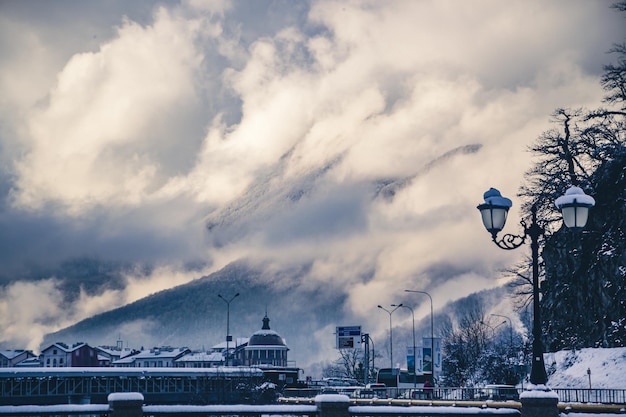 Landscape of the city against the background of high mountains in the snow, cold and winter