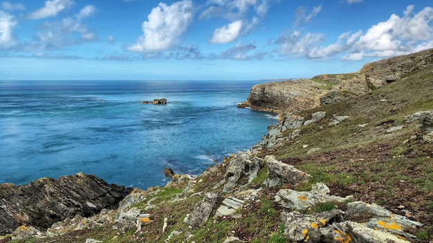 Landscape of cliffs surrounded by the sea under the sunlight and a blue cloudy sky