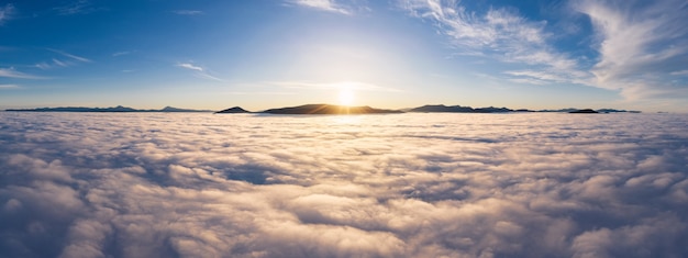 Landscape above the clouds with mountain peaks at sunrise. Dramatic cloudscape from aerial view.