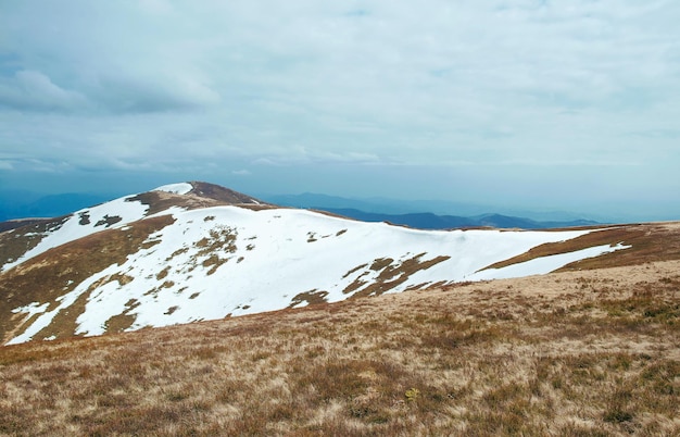 Landscape of great snowy peak of the mountains in spring in the cloudy day