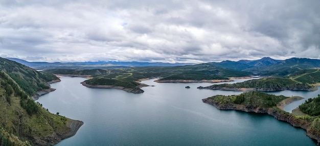 Landscape of a lake between the green mountains on a cloudy day aerial view