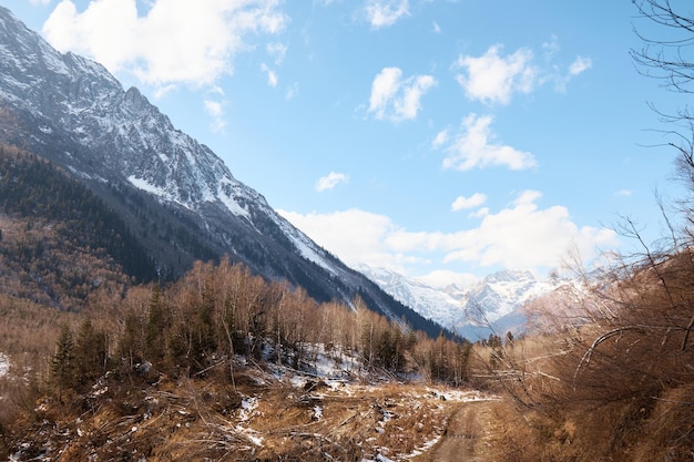 Landscape in the mountains, river and coniferous forest, autumn, the first snow on the slopes, fallen trees and shrubs