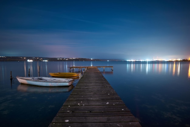 Landscape photo of a jetty and boats on lake at night in Varna Bulgaria