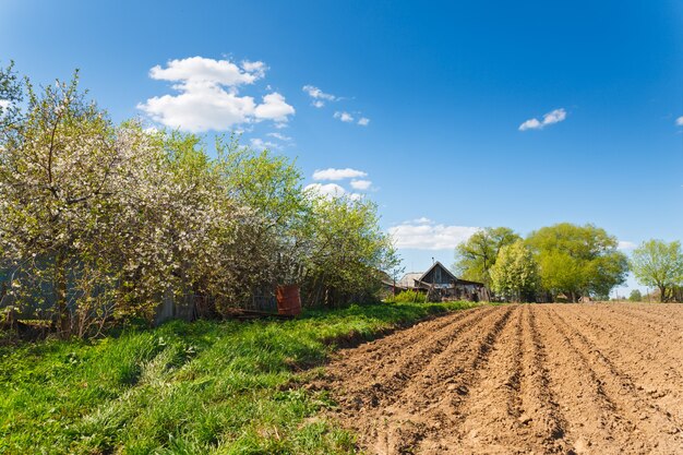 Landscape plowed field on a background of rural houses