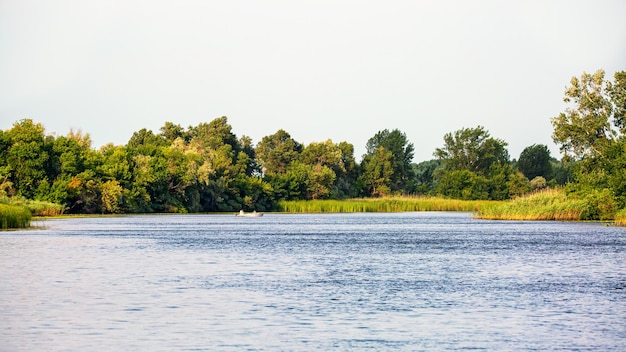 Landscape on the river with a fisherman on a boat