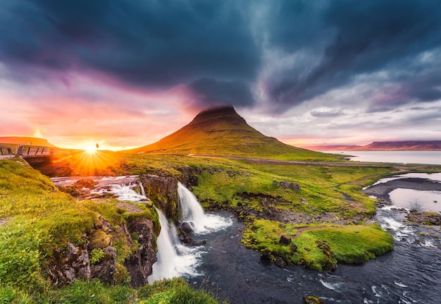 Landscape of sunset over Kirkjufell mountain with Kirkjufellsfoss waterfall and colorful pileus cloud on summer at Iceland