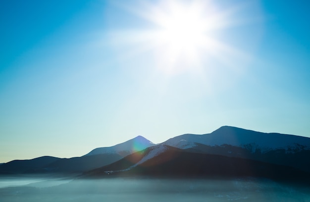 Landscape of white mountain valley covered with snow on clear winter frosty day