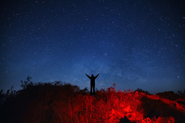 Landscape with milky way galaxy Starry night sky with stars and silhouette of a standing sporty man