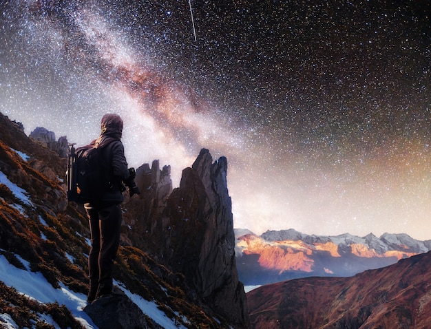 Landscape with milky way, Night sky  stars and silhouette of a standing photographer man on the mountain.