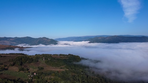 Landscape with mountains and clouds covering valley, scenic view in nature.