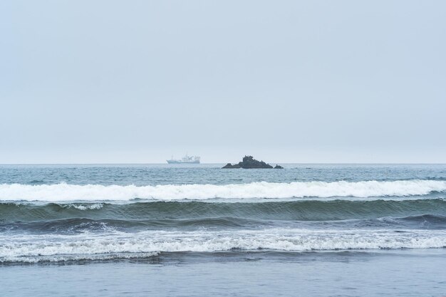 Landscape with a sea rock and a sailing ship in the distance