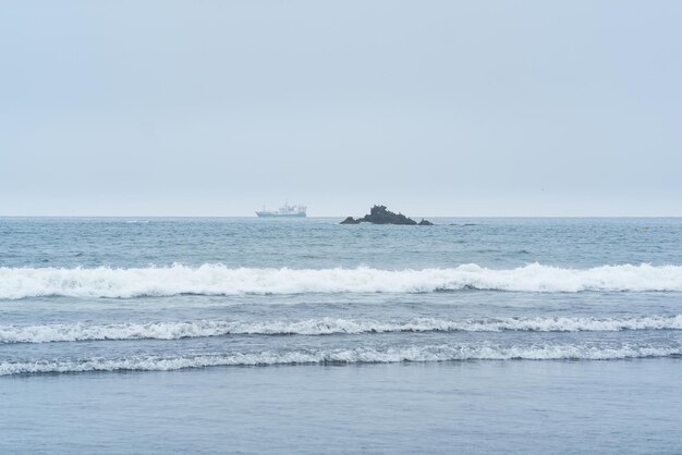 Landscape with a sea rock and a sailing ship in the distance