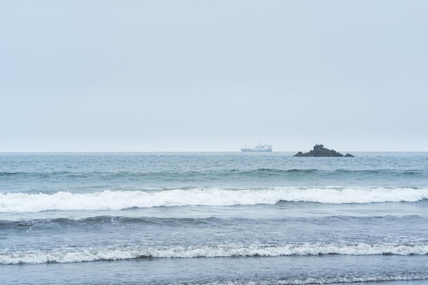 Landscape with a sea rock and a sailing ship in the distance