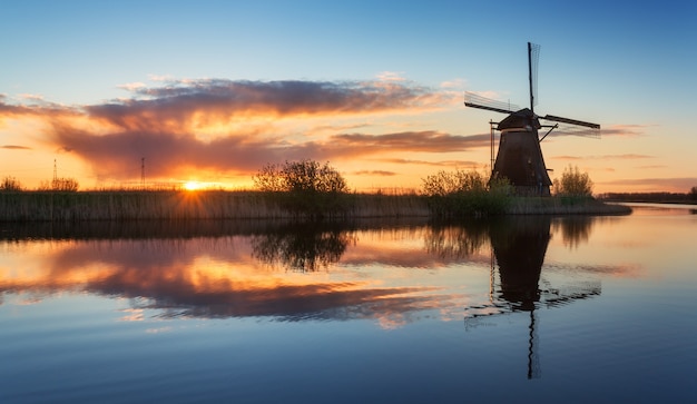 Landscape with traditional dutch windmills at colorful sunrise, beautiful sky