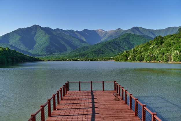 Landscape of wooden pier with beautiful lake and mountains view. Serene quiet peaceful atmosphere in nature